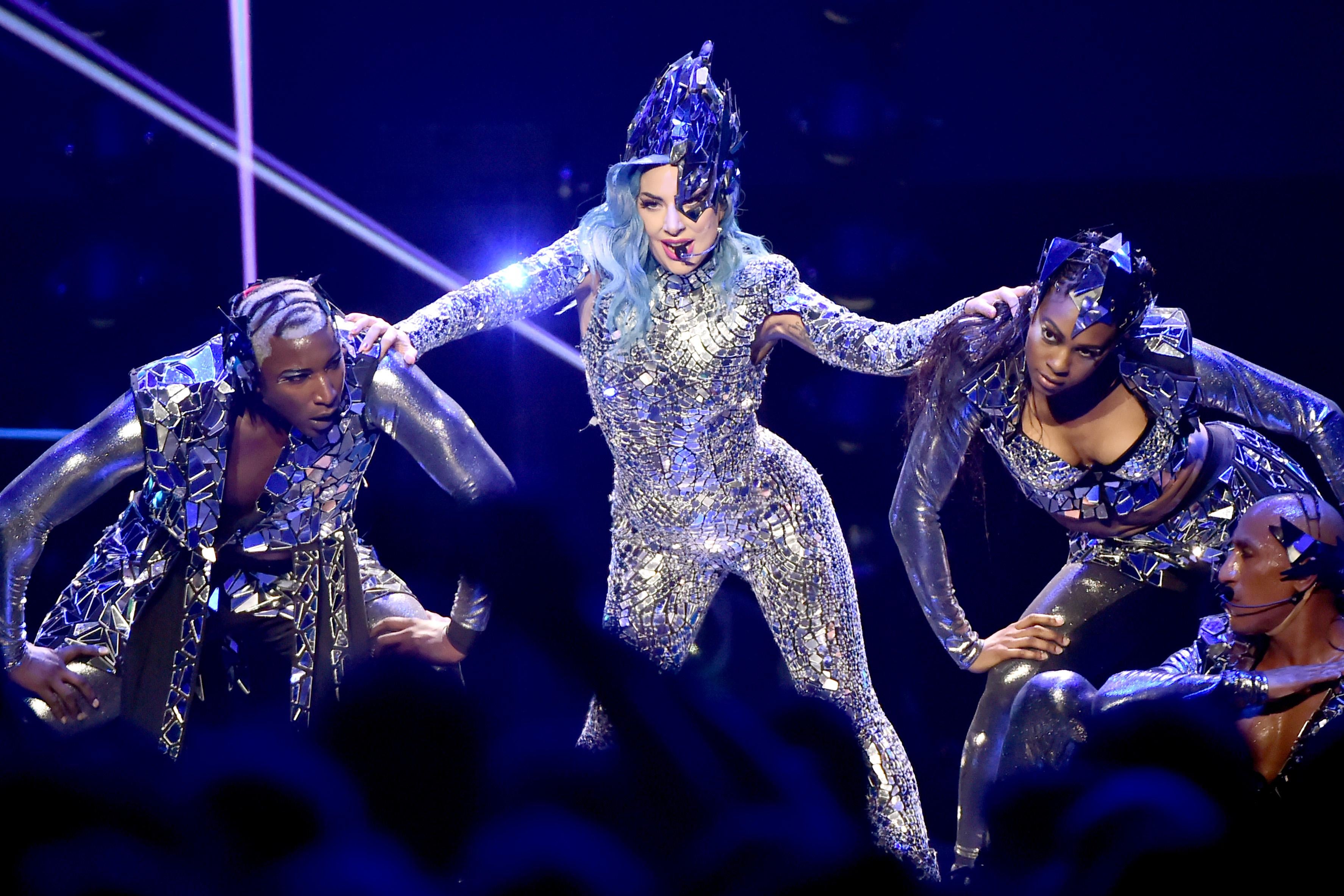 Lady Gaga performs onstage in a sparkling suit with backup dancers.