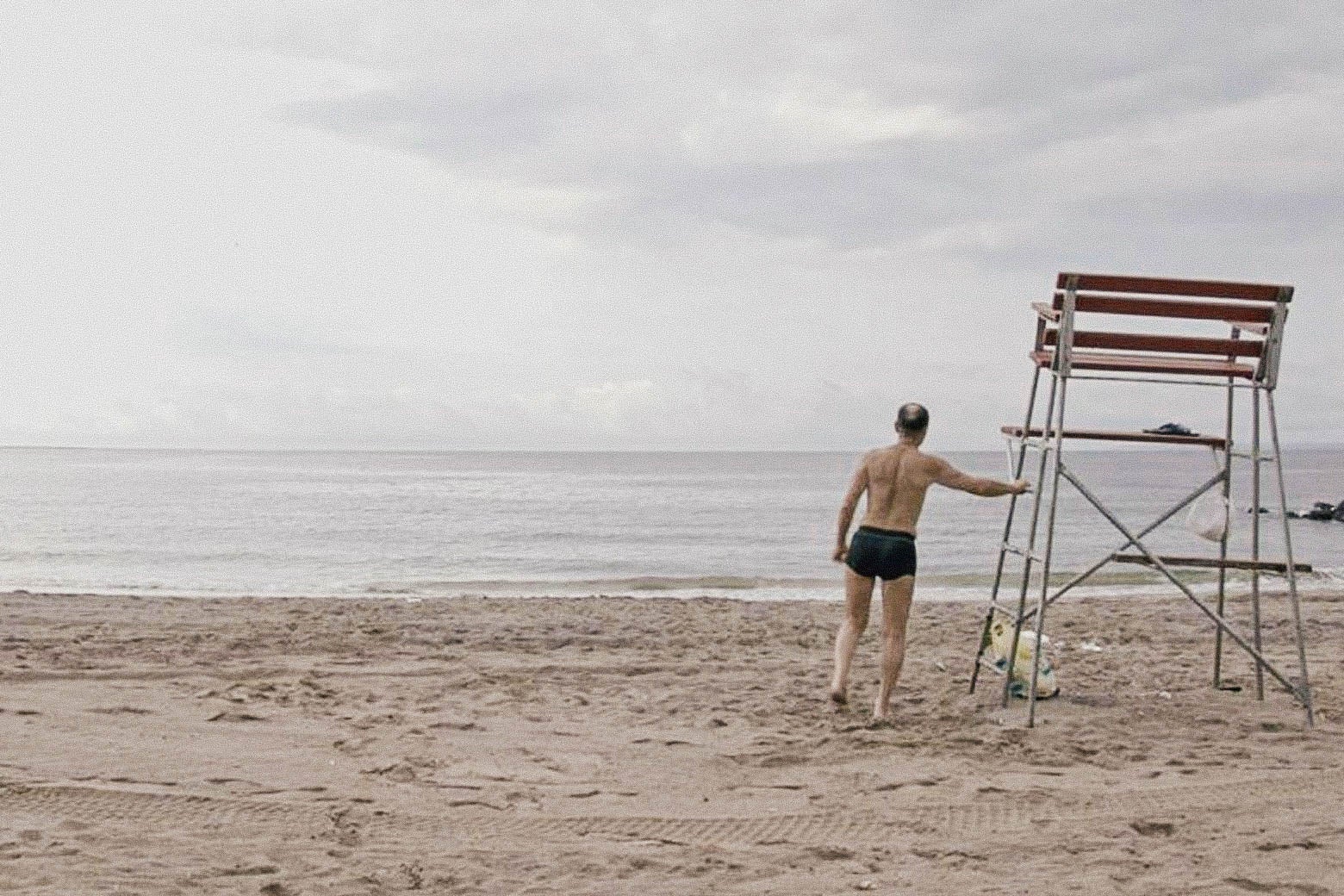 A man on the beach in swim trunks.