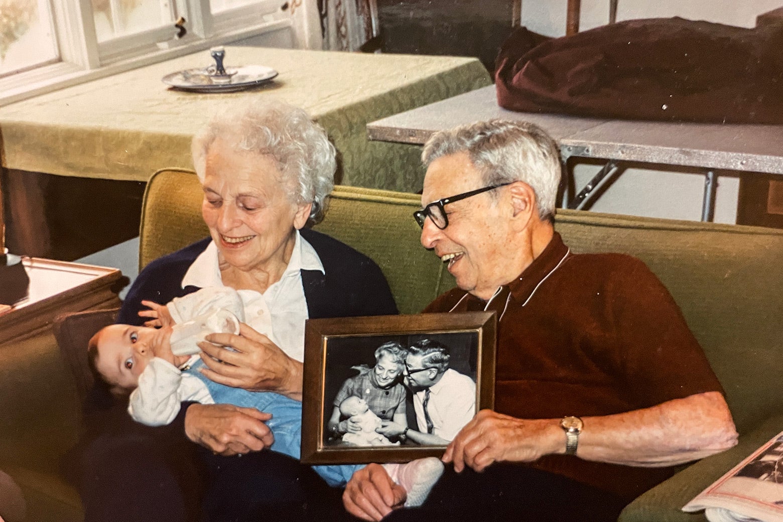George Michaels, with his wife and one of his granddaughters, holding a photo of his first granddaughter.