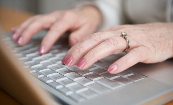 Older woman typing on a laptop.