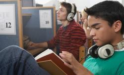 Portrait of two teenage boys wearing headphones in a library