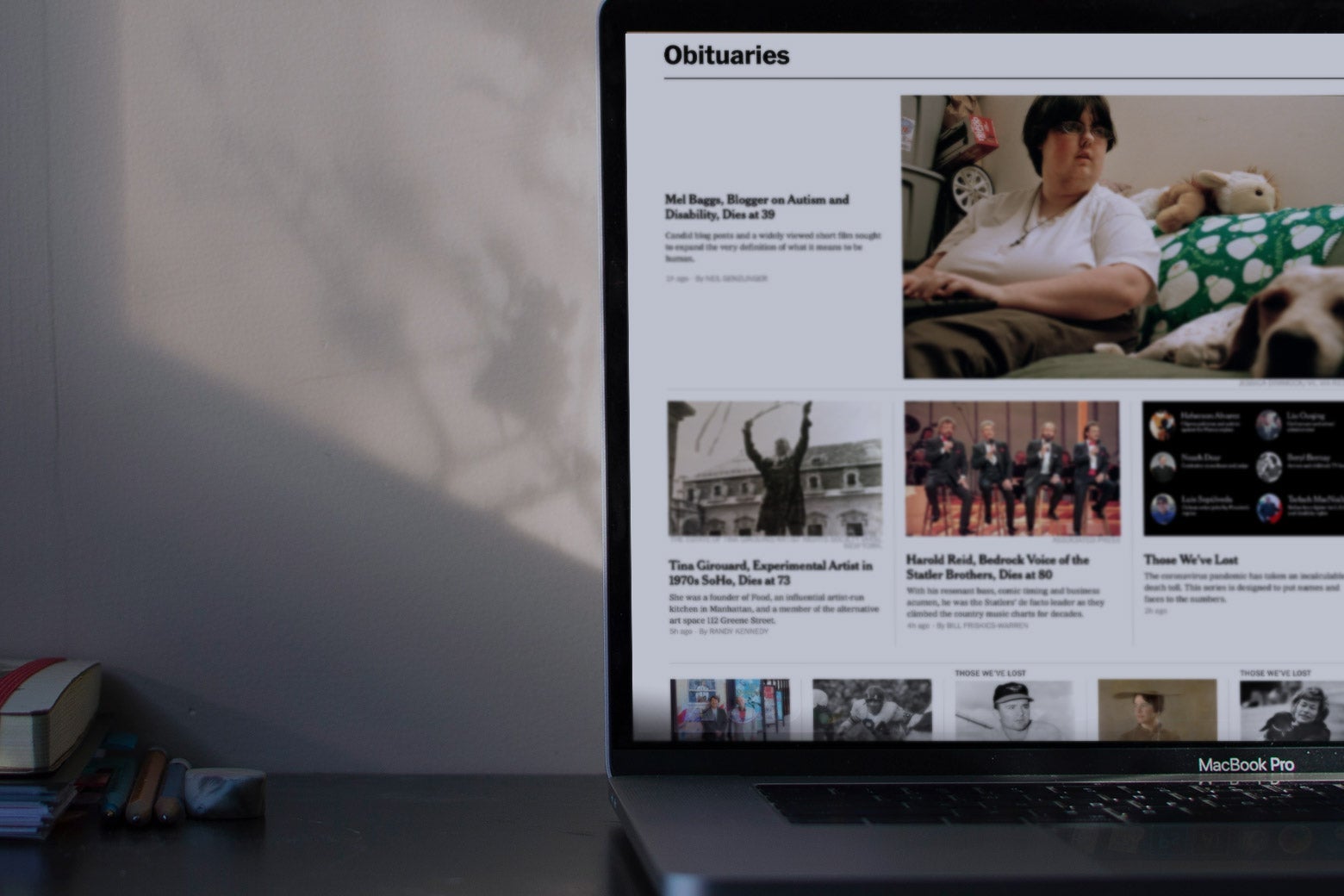 The New York Times Obituaries page on a laptop on a desk.