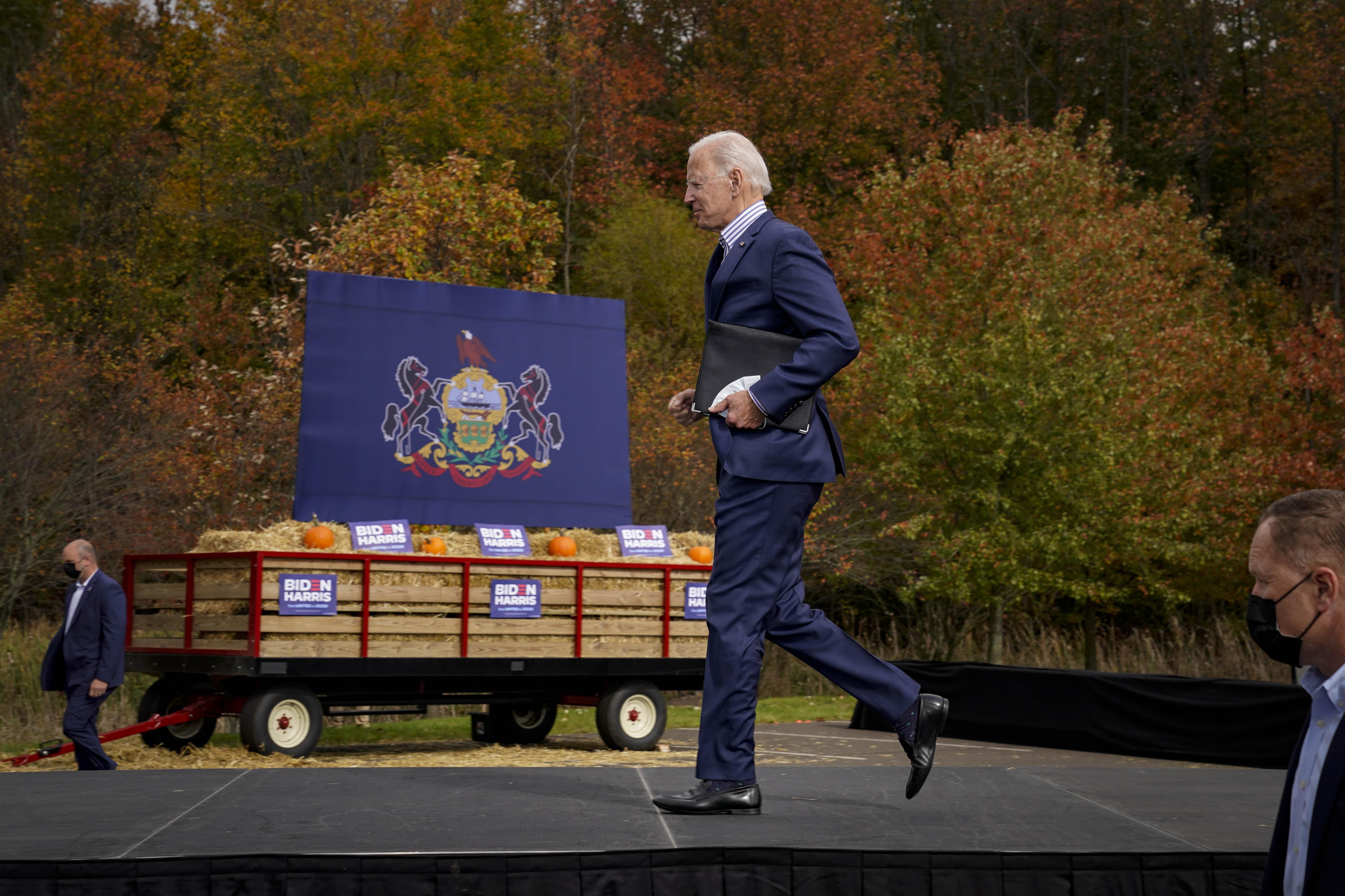 Joe Biden jogs offstage, with a cart full of hay in the background