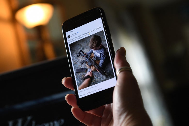 Photo of a toddler boy holding an AR-style rifle in a Daniel Defense tweet displayed on a cellphone