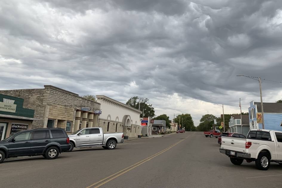 A downtown with pickup trucks and SUVs parked along an empty road.