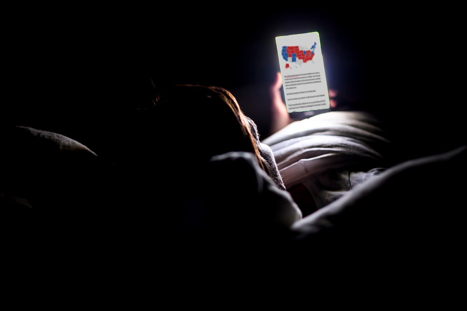 Person in bed, looking at election returns on a phone
