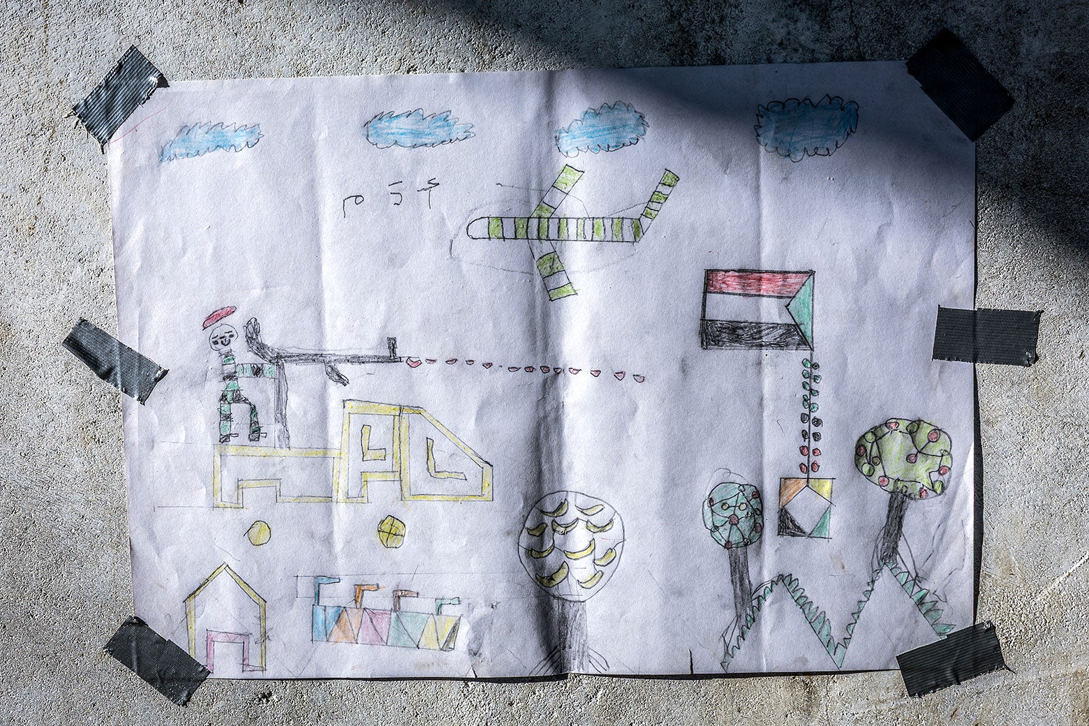 A hand-colored drawing showing a plane and a gunman is taped to a wall.