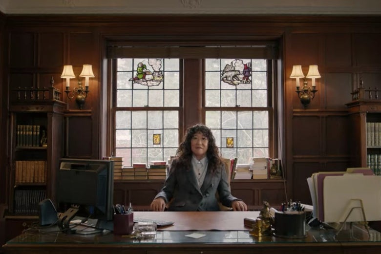 Dr. Kim sitting behind a desk in a grand-looking office, right before her chair breaks.