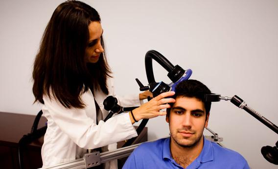 A doctor demonstrating a technique called transcranial magnetic stimulation, which affect neurons in the brain.