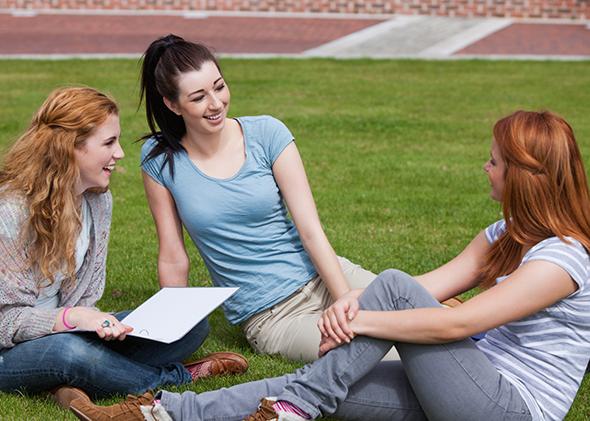 Young women sitting on a college campus lawn