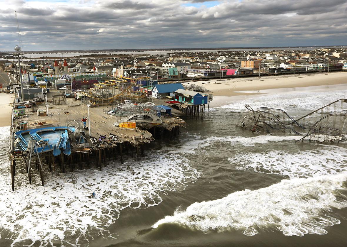Waves break in front of a destroyed amusement park wrecked by Hurricane Sandy.