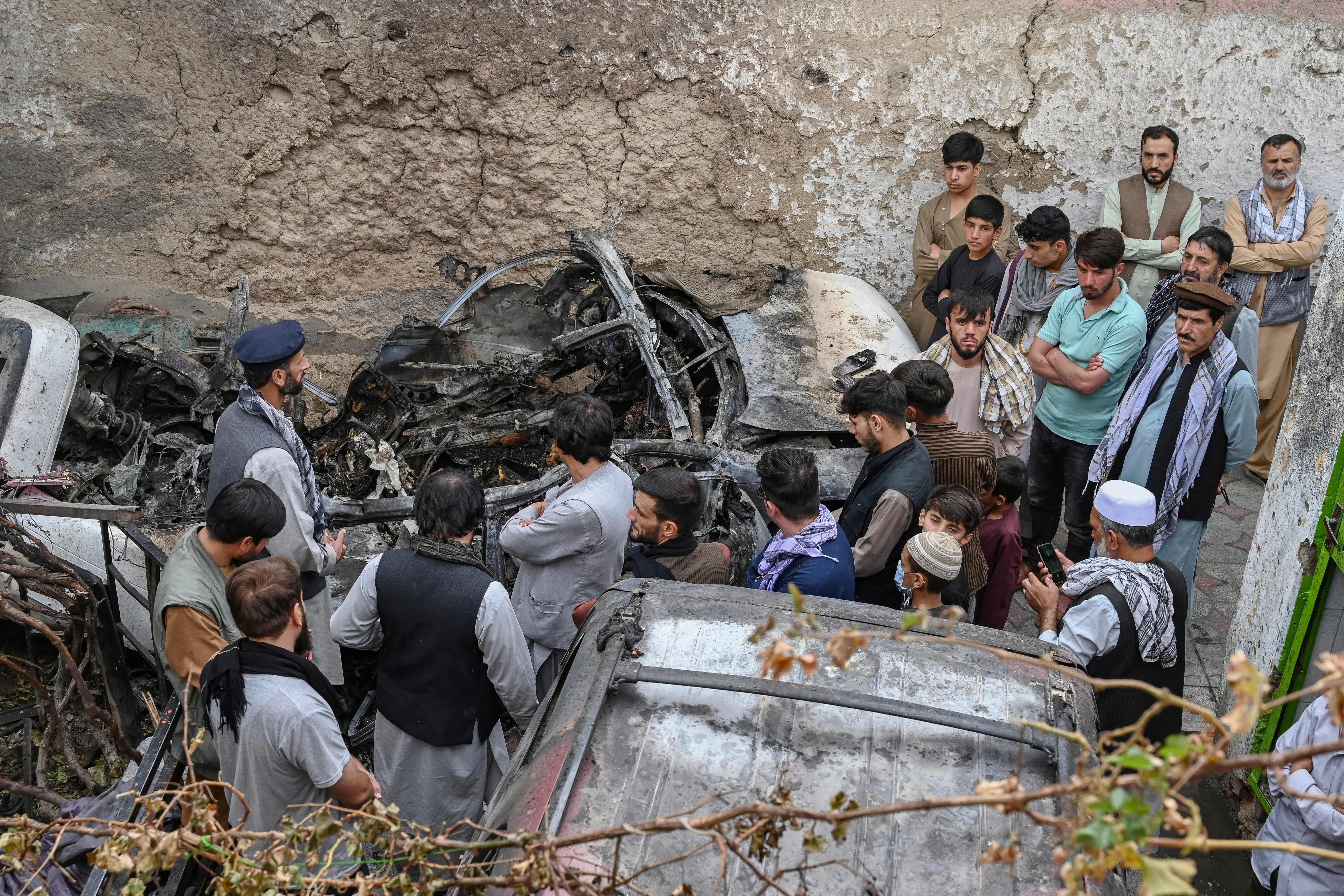 Afghan residents and family members of the victims gather next to a damaged vehicle inside a house, a day after a U.S. drone airstrike in Kabul on August 30, 2021. 