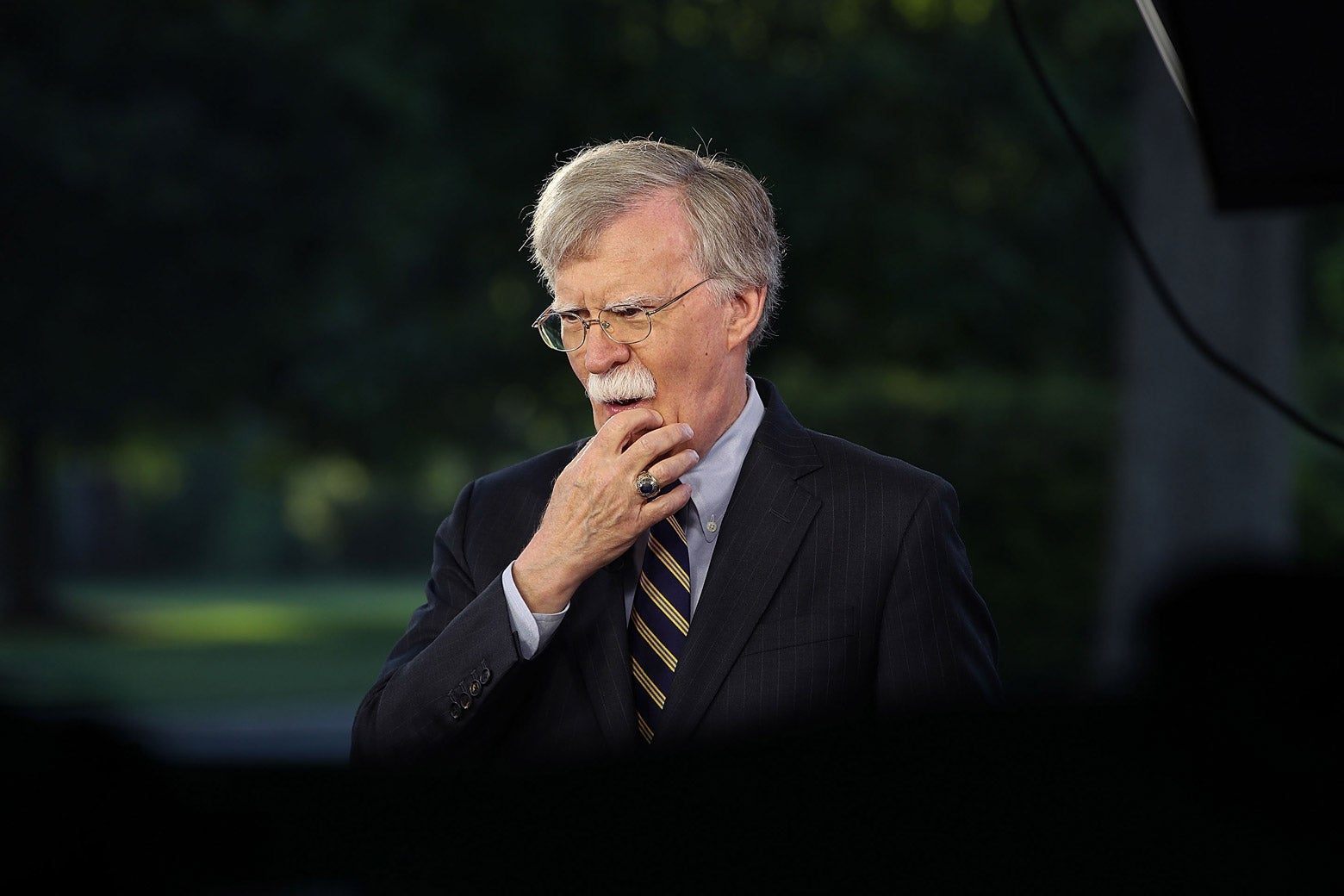 John Bolton strokes his chin while standing outside the White House.