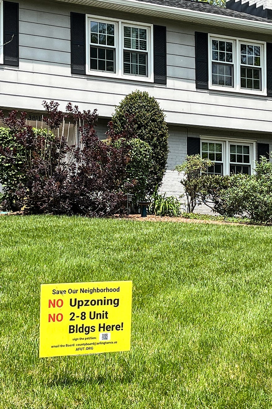 The front yard of a two-story single-family dwelling, with a yellow sign that reads, "NO upzoning. NO 2-8 Unit Buildings Here!"