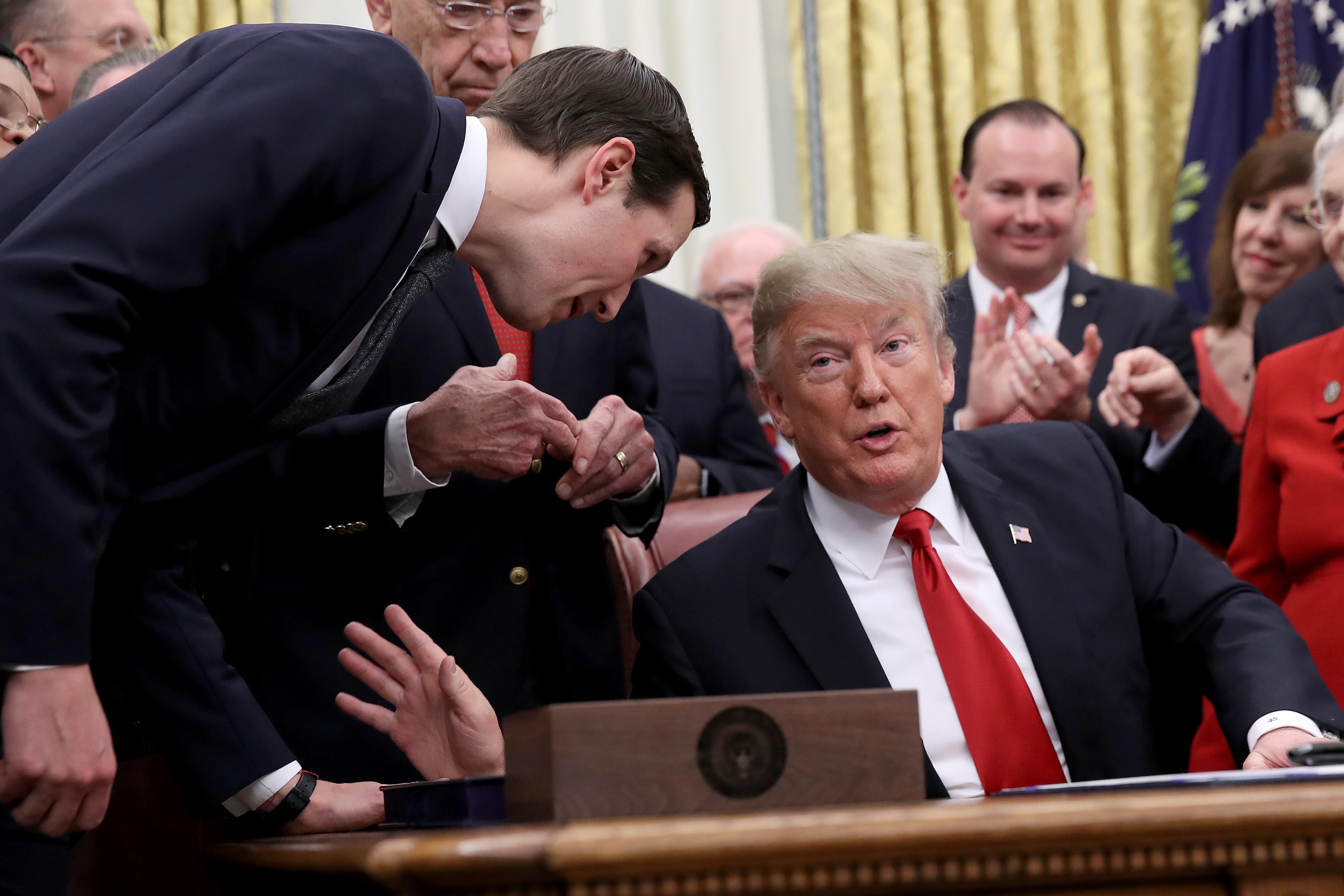Jared Kushner leans in to speak with President Donald Trump during the signing ceremony for the First Step Act and the Juvenile Justice Reform Act in the Oval Office of the White House December 21, 2018 in Washington, D.C. 