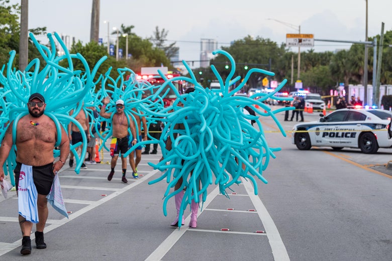 Parade participants walk away as police investigate the scene where a pickup truck drove into a crowd of people at a Pride parade on June 19, 2021 in Wilton Manors, Florida. 