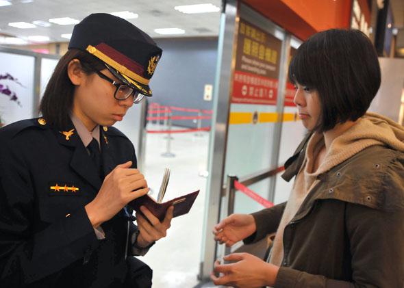 An airport security officer (L) checks a passenger's passport and boarding pass at Taipei Songshan Airport on March 10, 2014.  