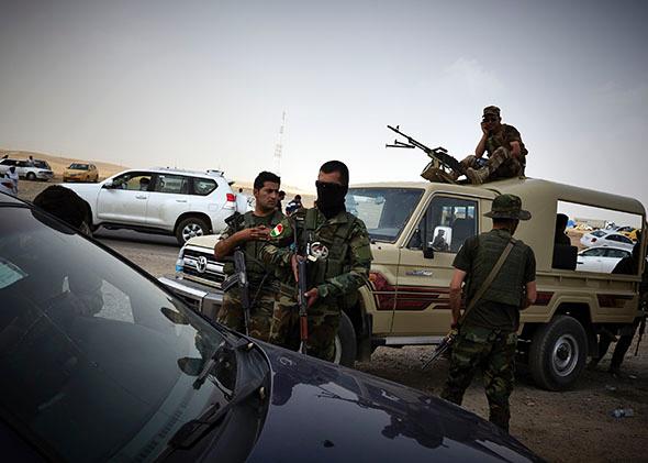 Kurdish soldiers provide security at a checkpoint as Iraqi refugee arrive fleeing from the city of Mosul. June 12, 2014.