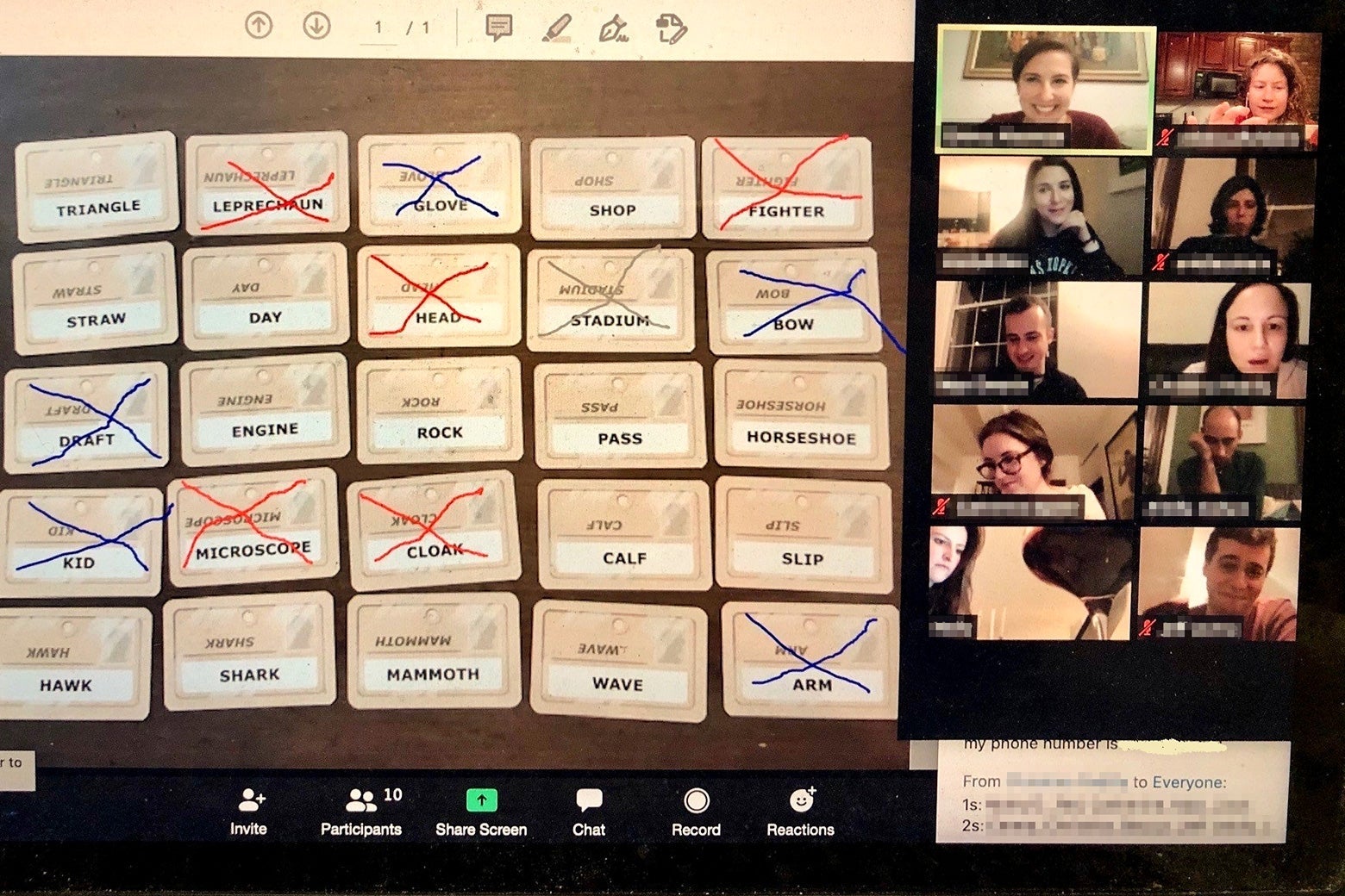 A photo of a laptop screen with a Zoom video conference on it, the largest square featuring cards laid out for the game Codenames and the smaller squares featuring players' faces.