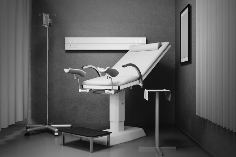 A medical exam table with stirrups, in black and white.