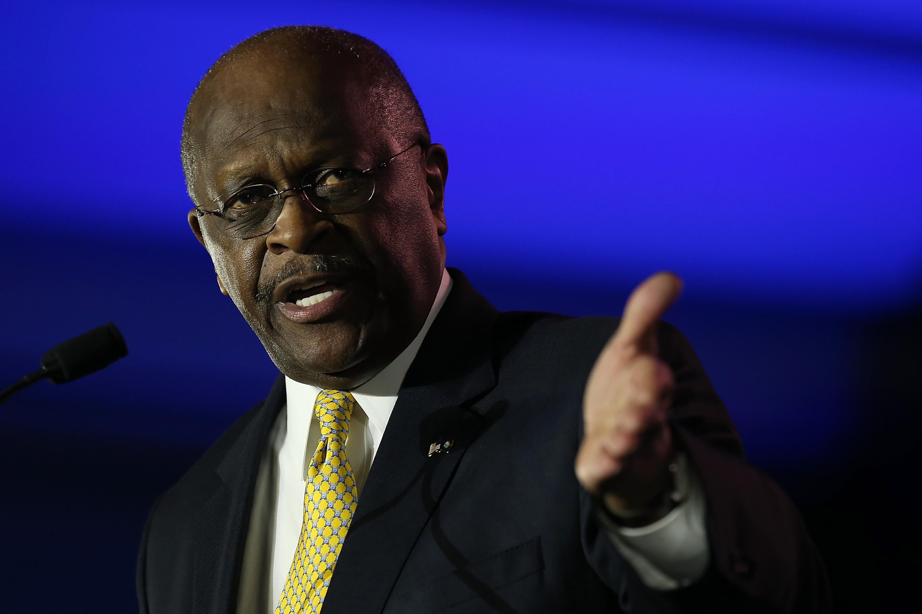 Herman Cain gesturing at a podium.