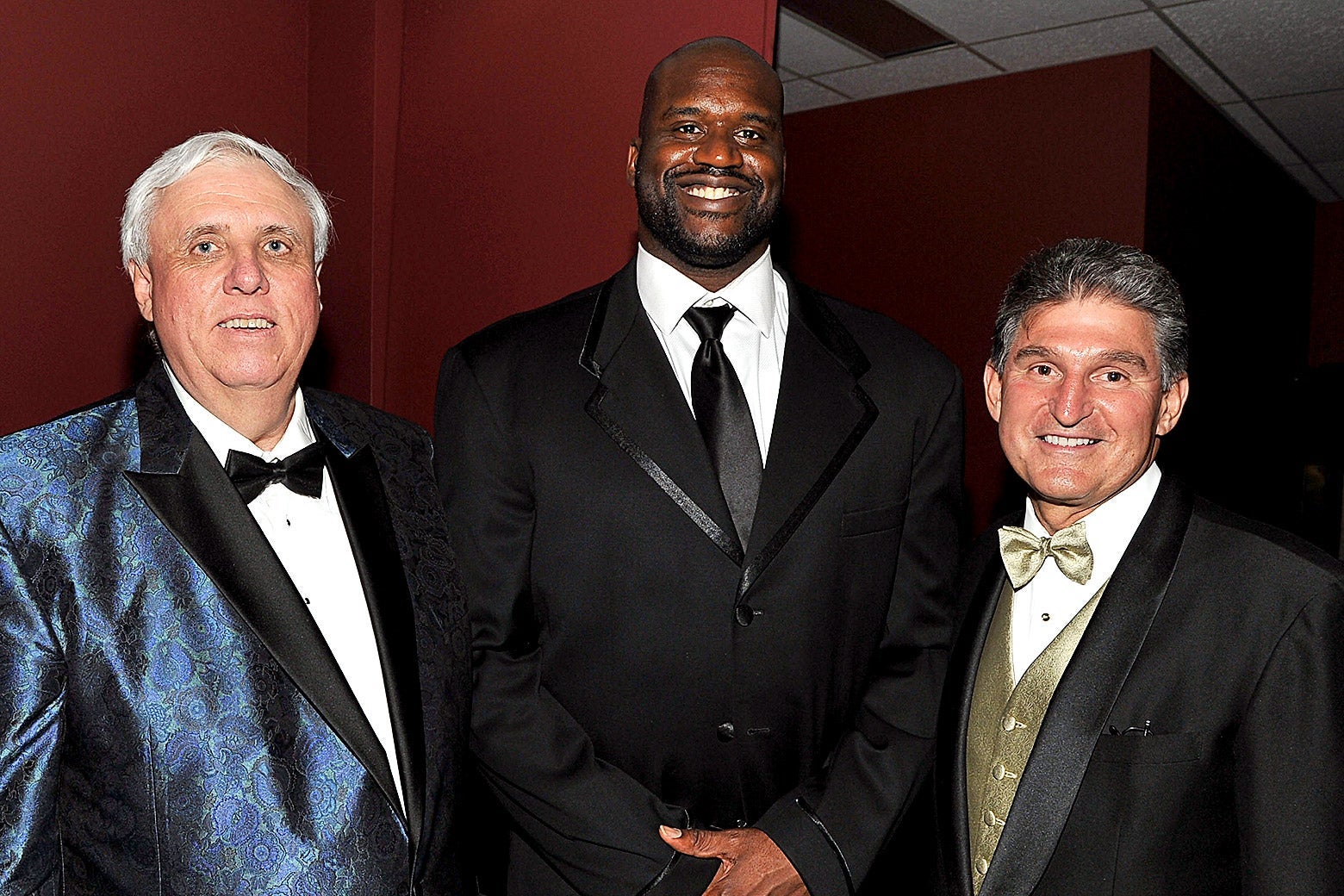 From L-R: Jim Justice, wearing a blue brocade suit jacket, Shaquille O'Neal wearing a black suit and tie, and Joe Manchin wearing a three-piece suit with a gold vest and bow tie.