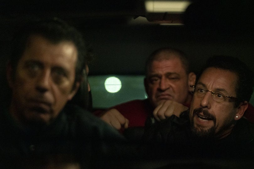 Adam Sandler in a car with two other men.