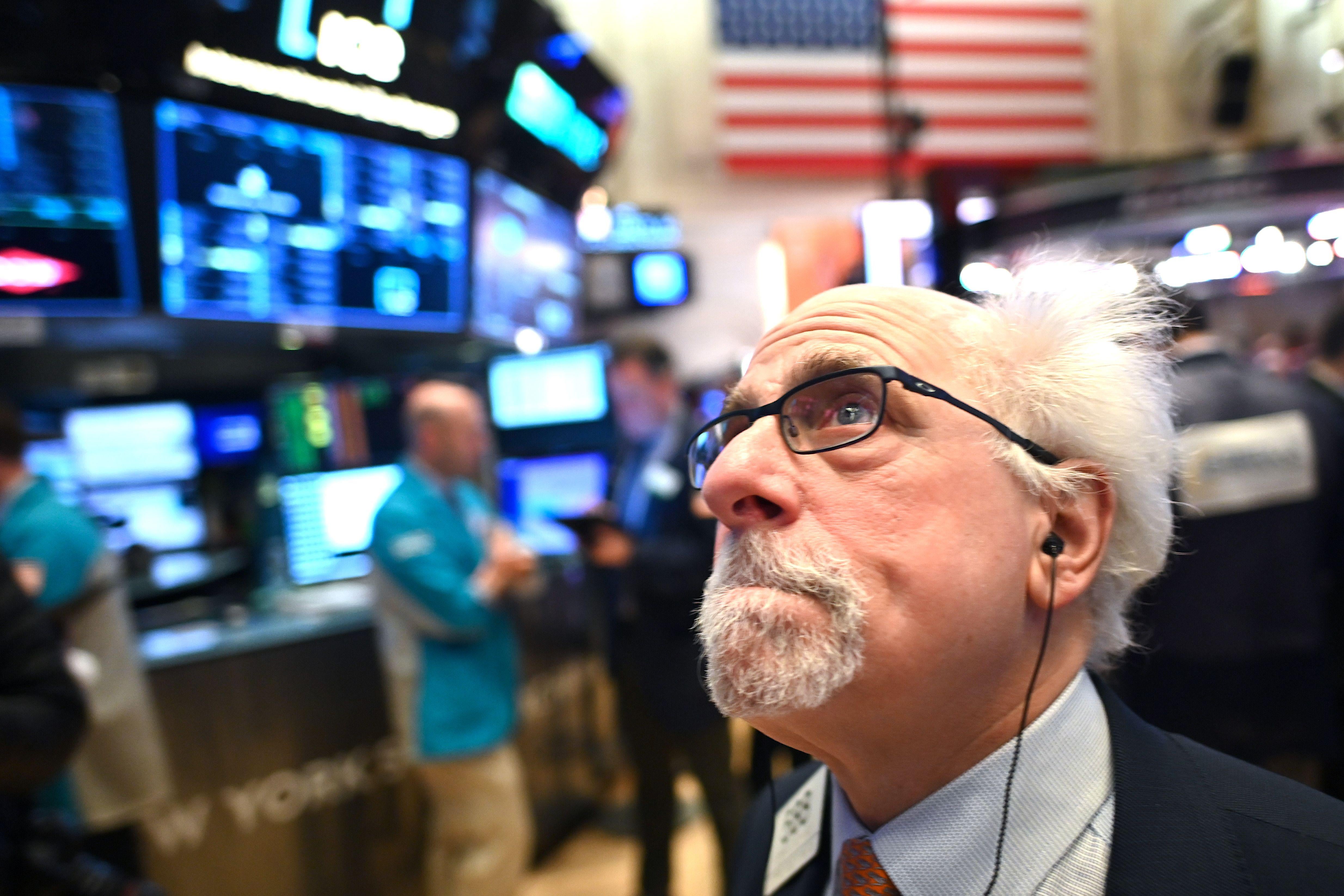 A trader with Doc Brown hair stands on the floor of the NYSE, looking up nervously and clenching his teeth