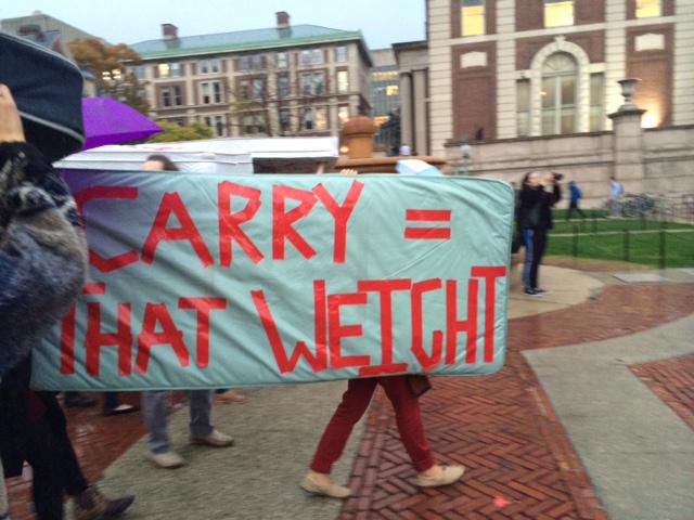Students on Columbia Univ campus with mattress that says carry that weight on it