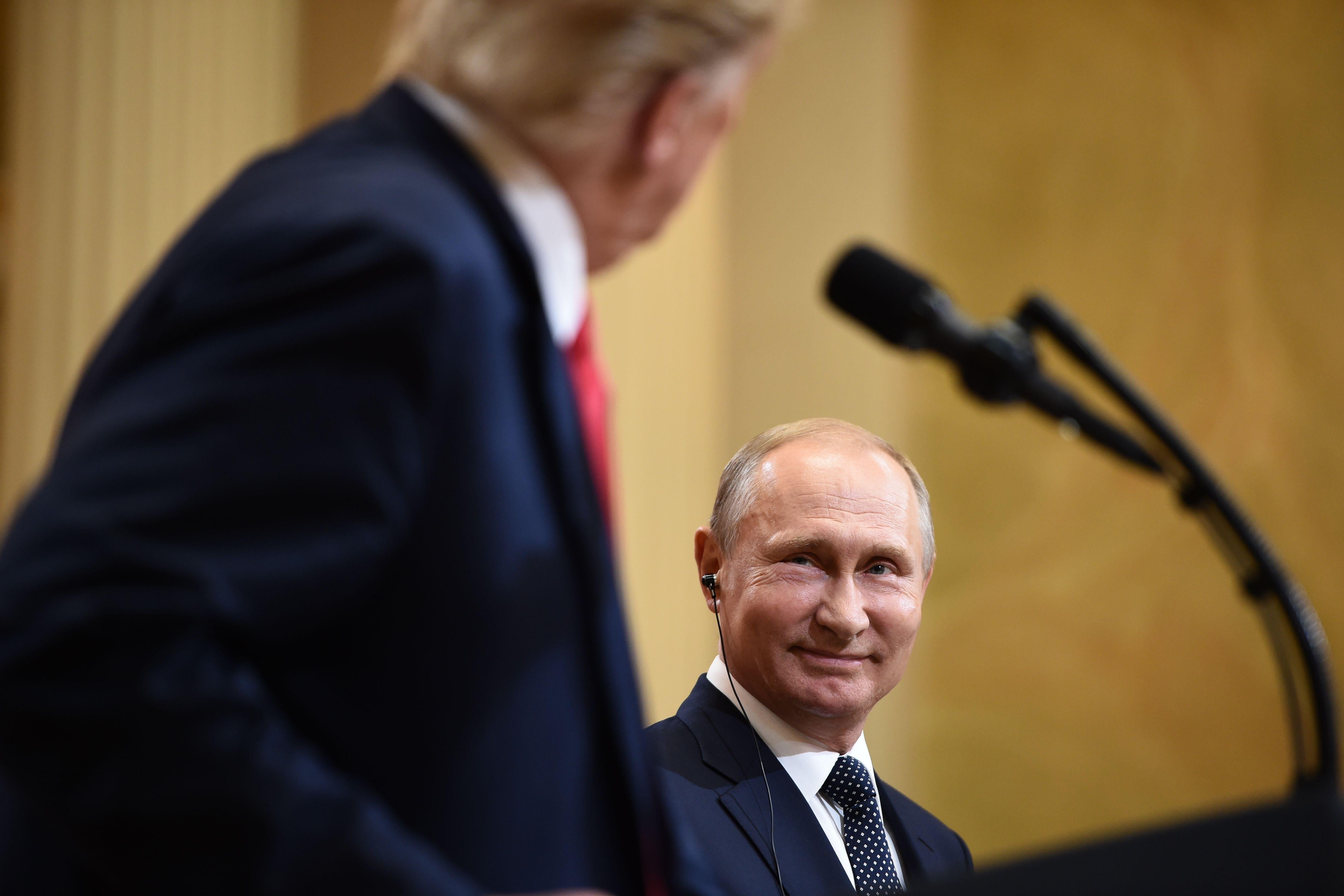 Putin smiles as Trump looks on.