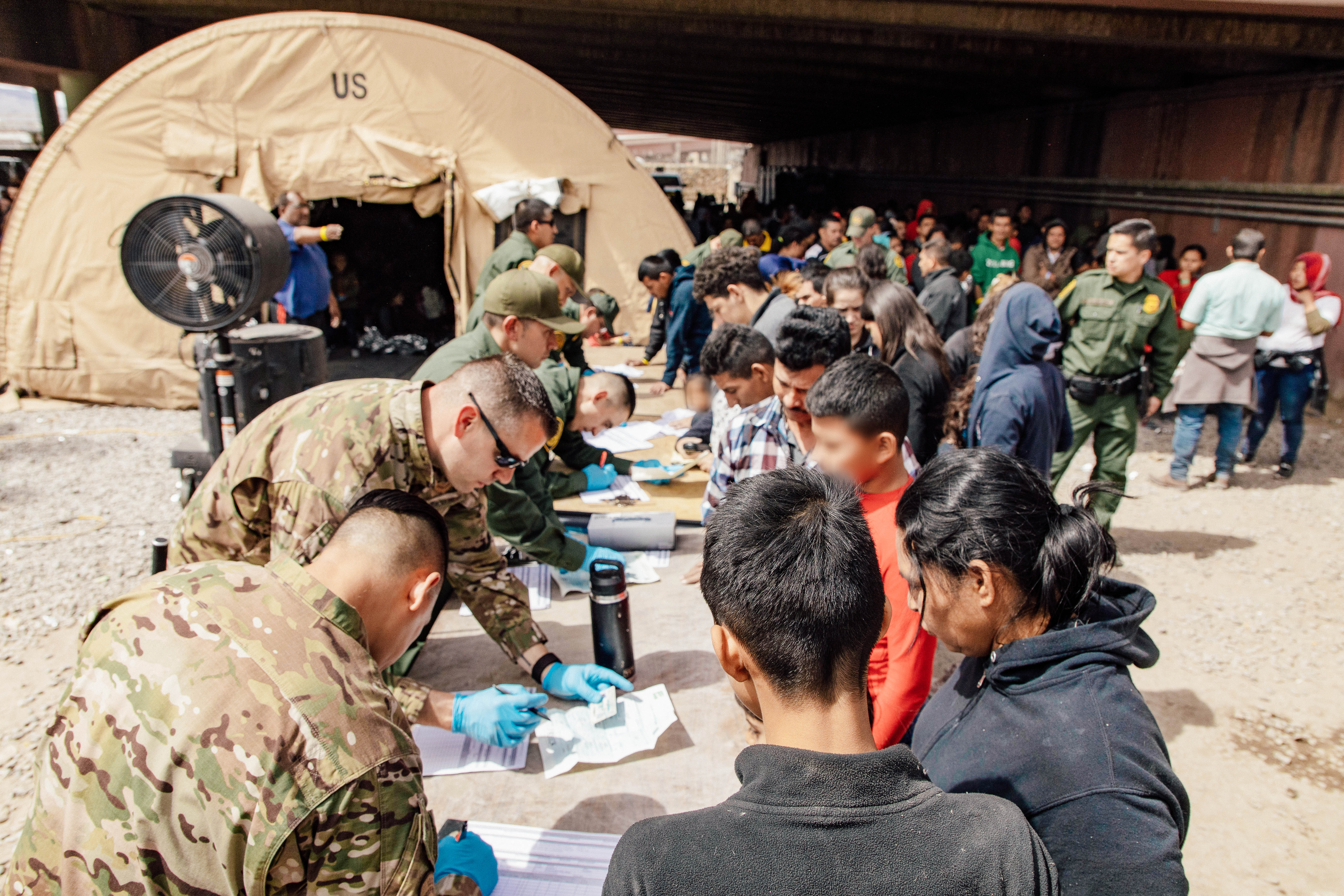 U.S. Border Patrol agents, including members of U.S. Border Patrol's BORSTAR teams (in tactical uniforms) provide food, water, and medical screening to migrants at a processing center in El Paso, Texas on March 22.