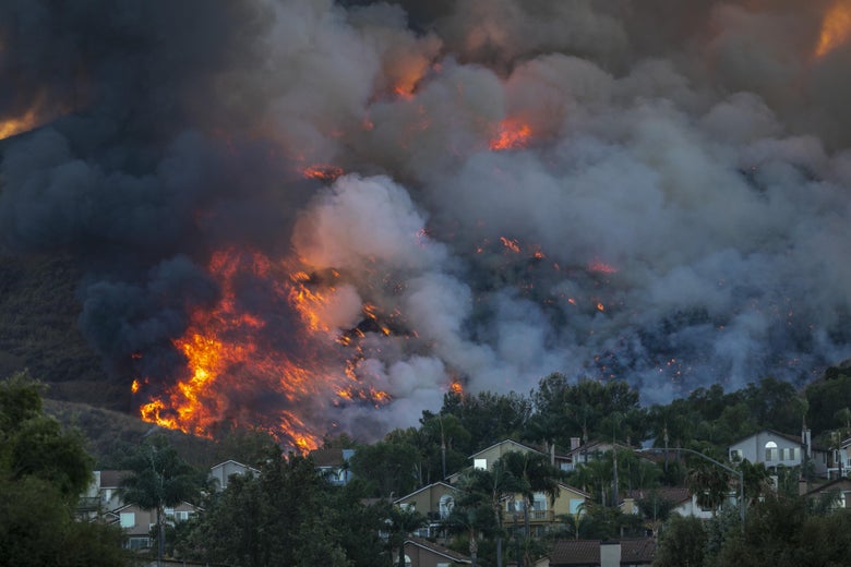 Smoke and flames by homes in heavily wooded hills