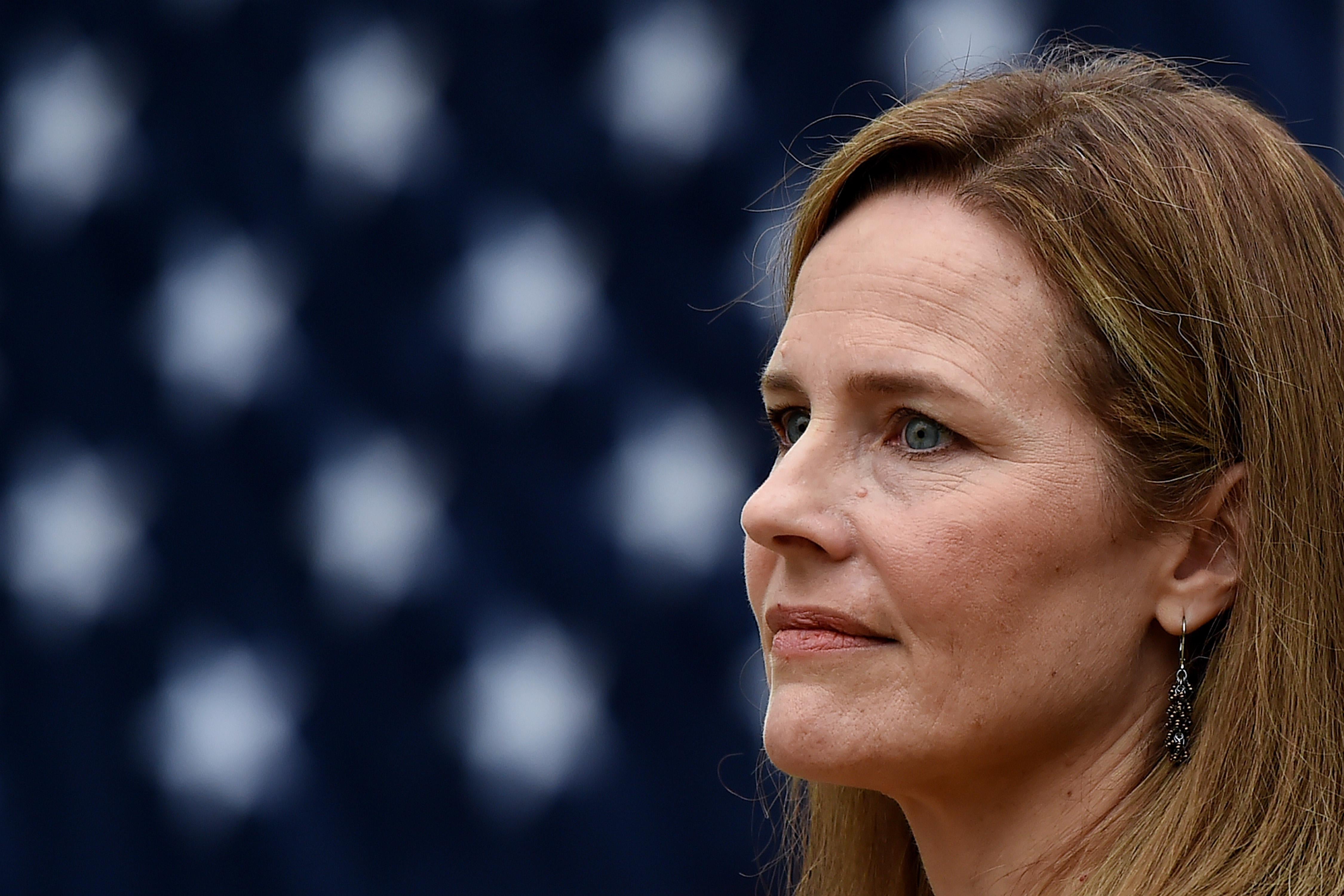 Amy Coney Barrett in profile with an American flag behind her.