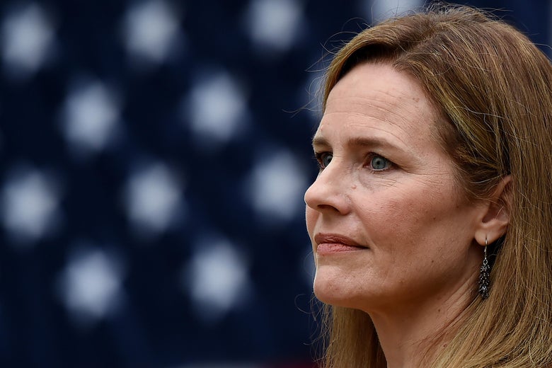 Amy Coney Barrett in profile with an American flag behind her.