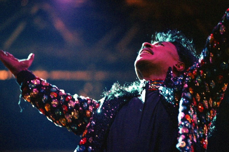 He looks up, full of the glory of god, in shiny multicolored sequins