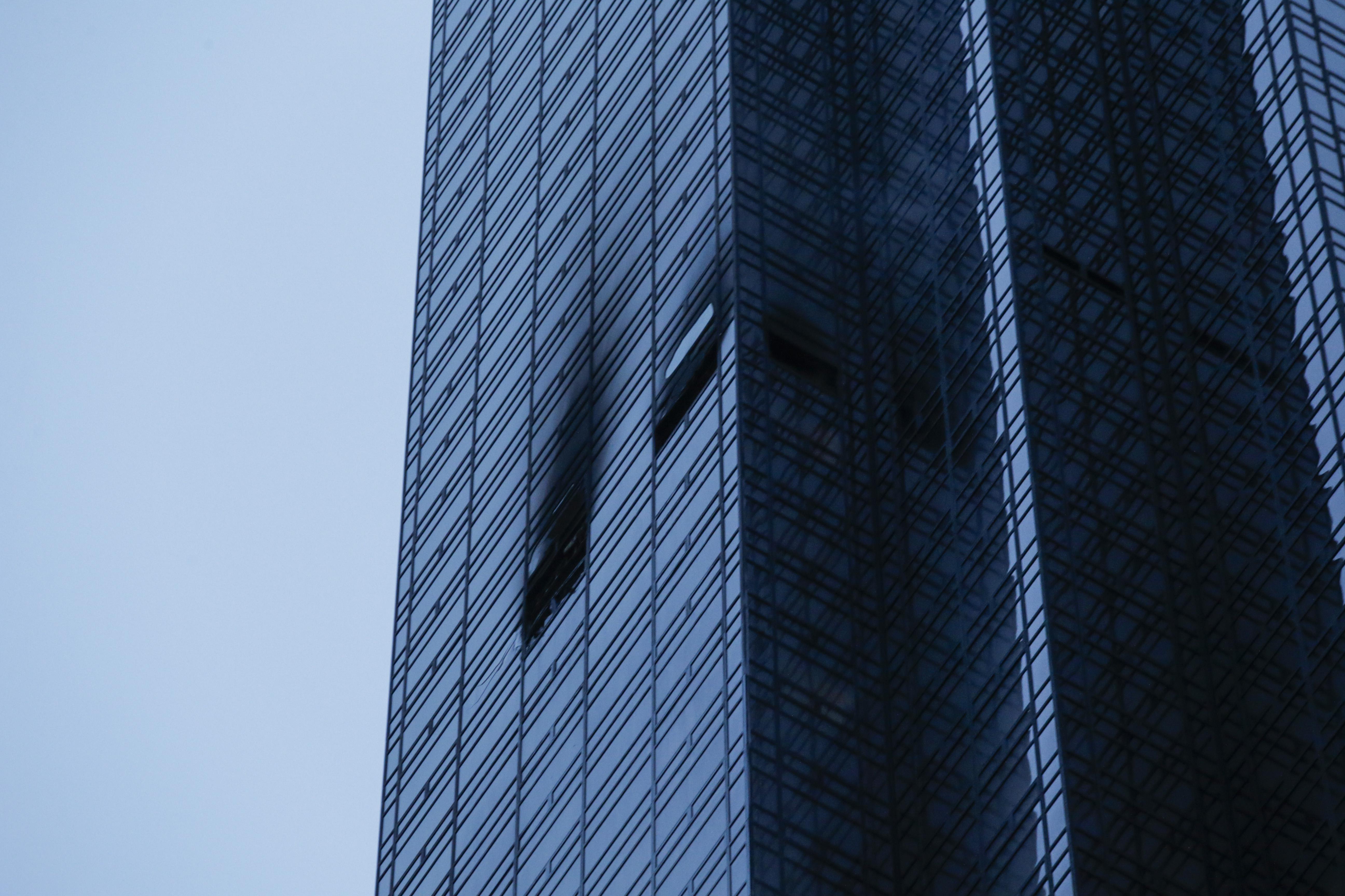 On the side of Trump Tower, two windows are burnt and broken.