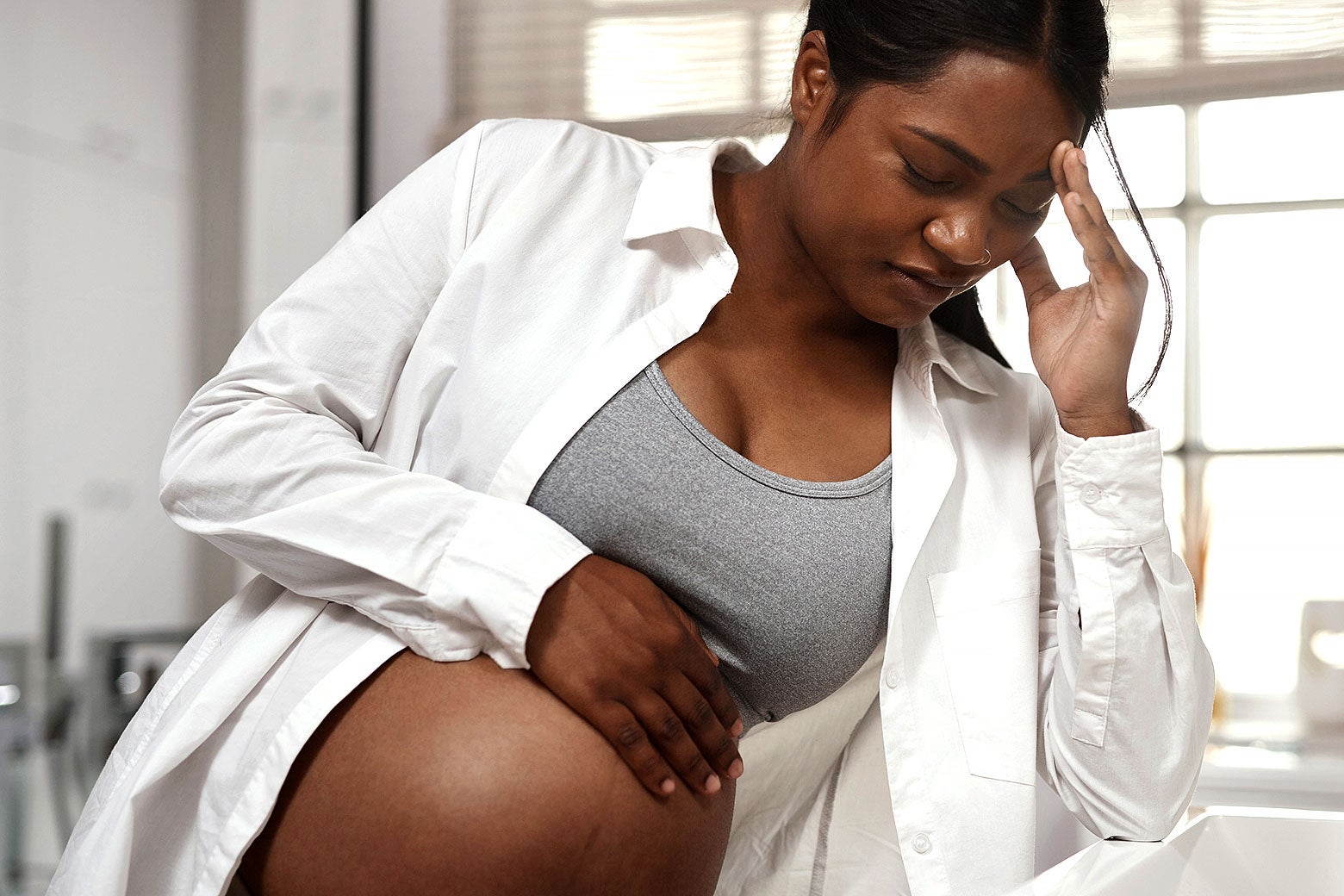 A pregnant woman holding her midsection in distress.