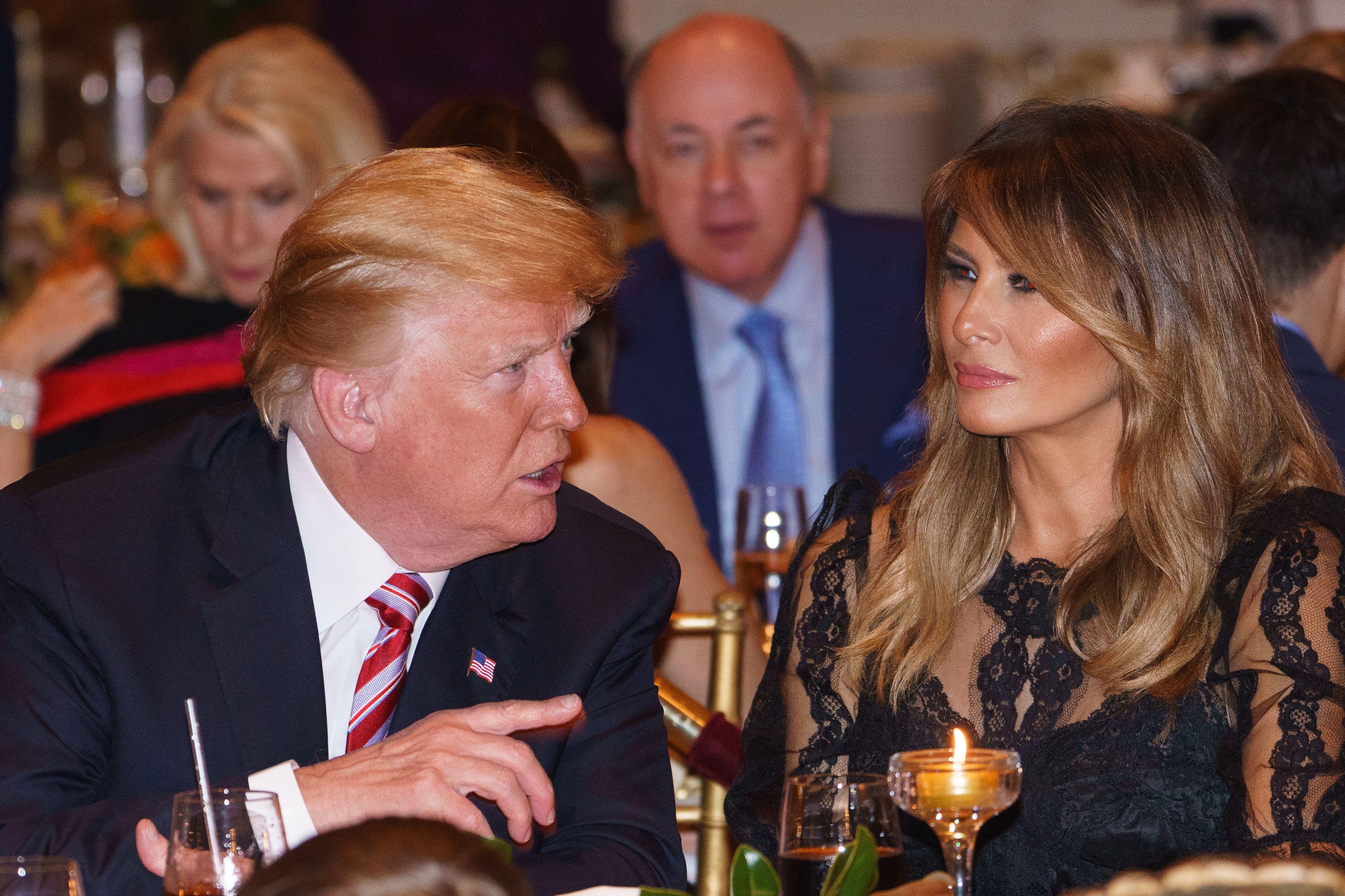 Donald Trump and Melania Trump seated at a fancy dinner.