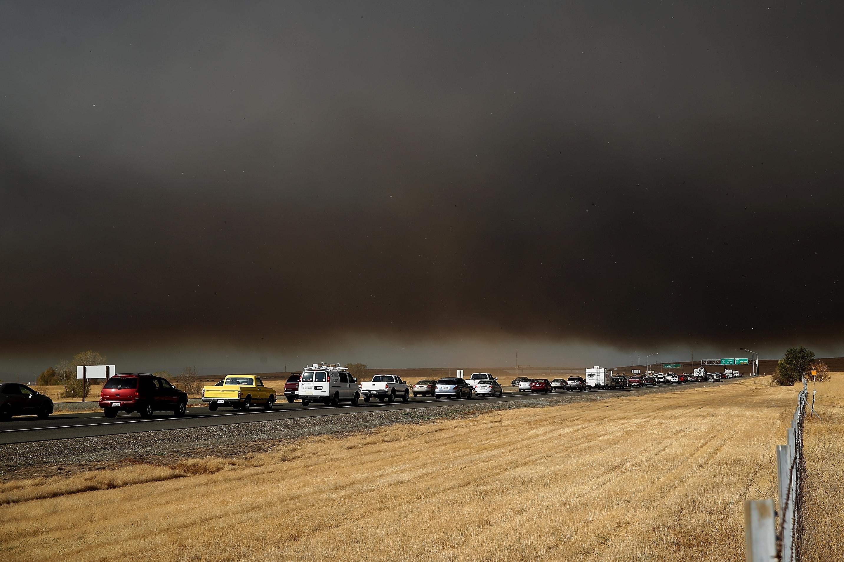 Cars stuck in traffic, with smoke overhead.