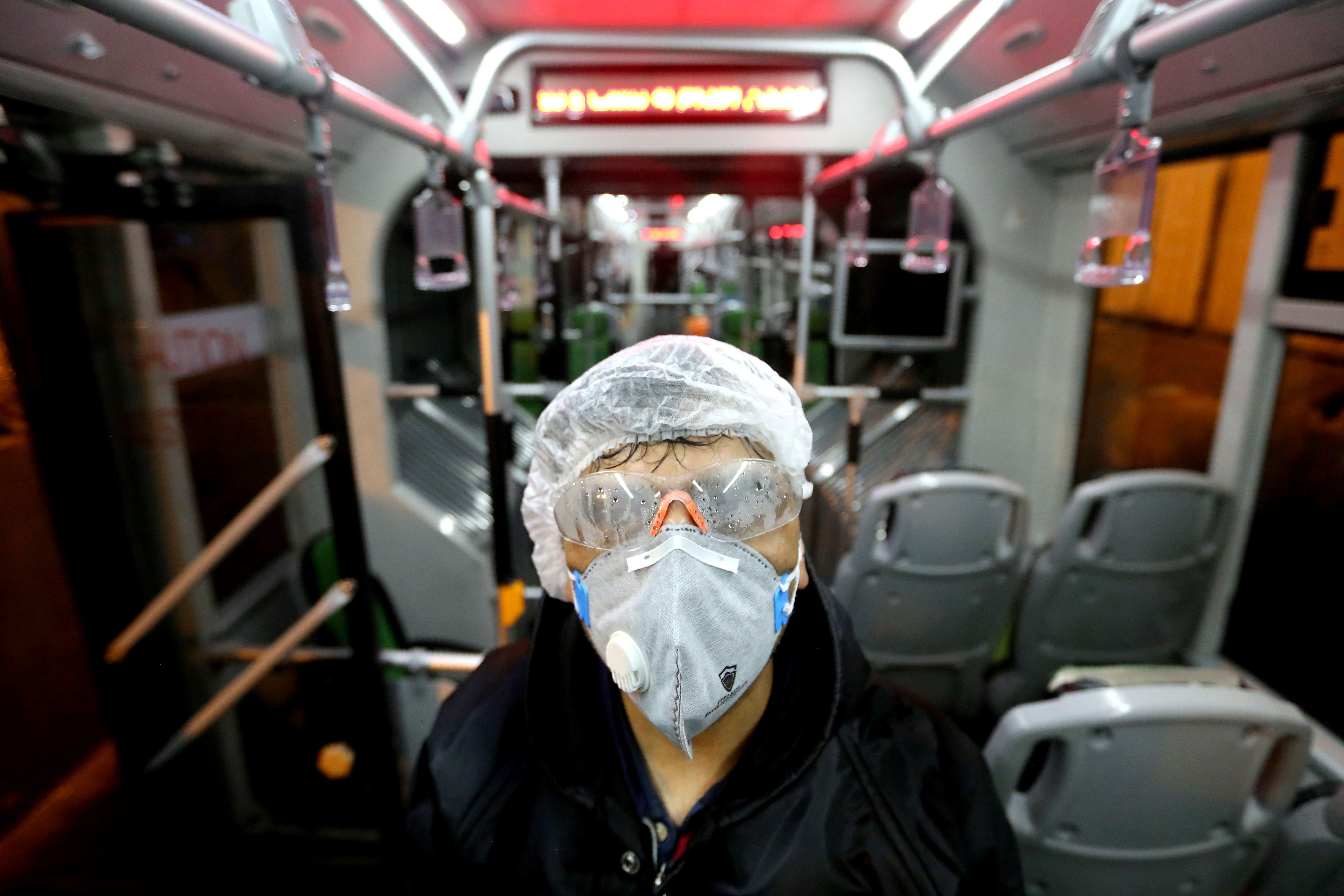 A man in a mask and protective goggles on an empty bus.