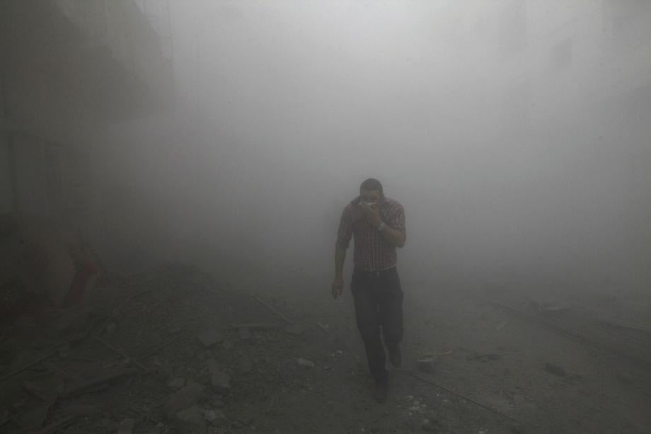 A man runs among rubble as smoke rises from buildings damaged by what activists said were missiles fired by a Syrian air force fighter jet loyal to President Bashar al-Assad in Raqqa province, eastern Syria on March 12, 2013.