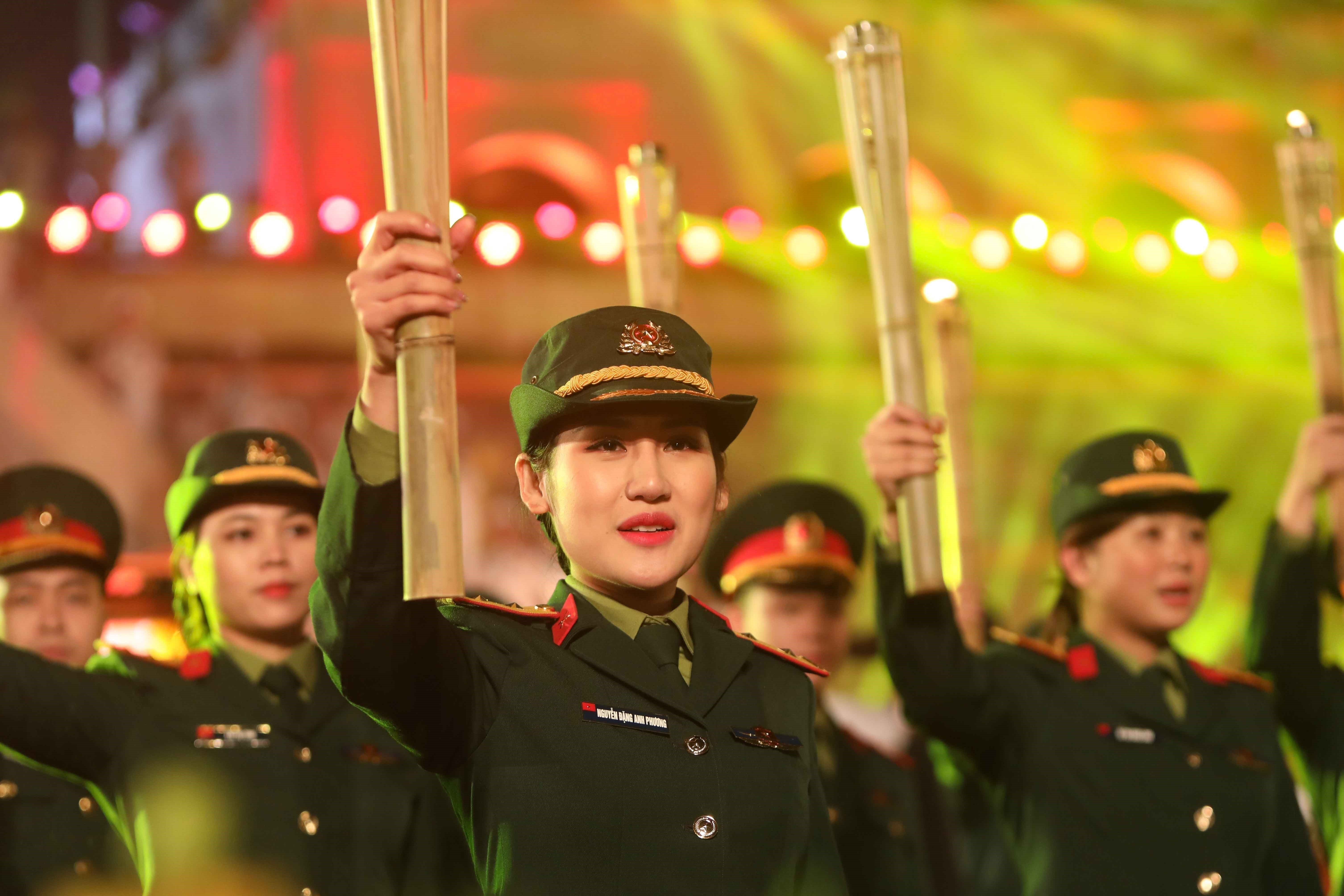 Women in uniform hold up torches.