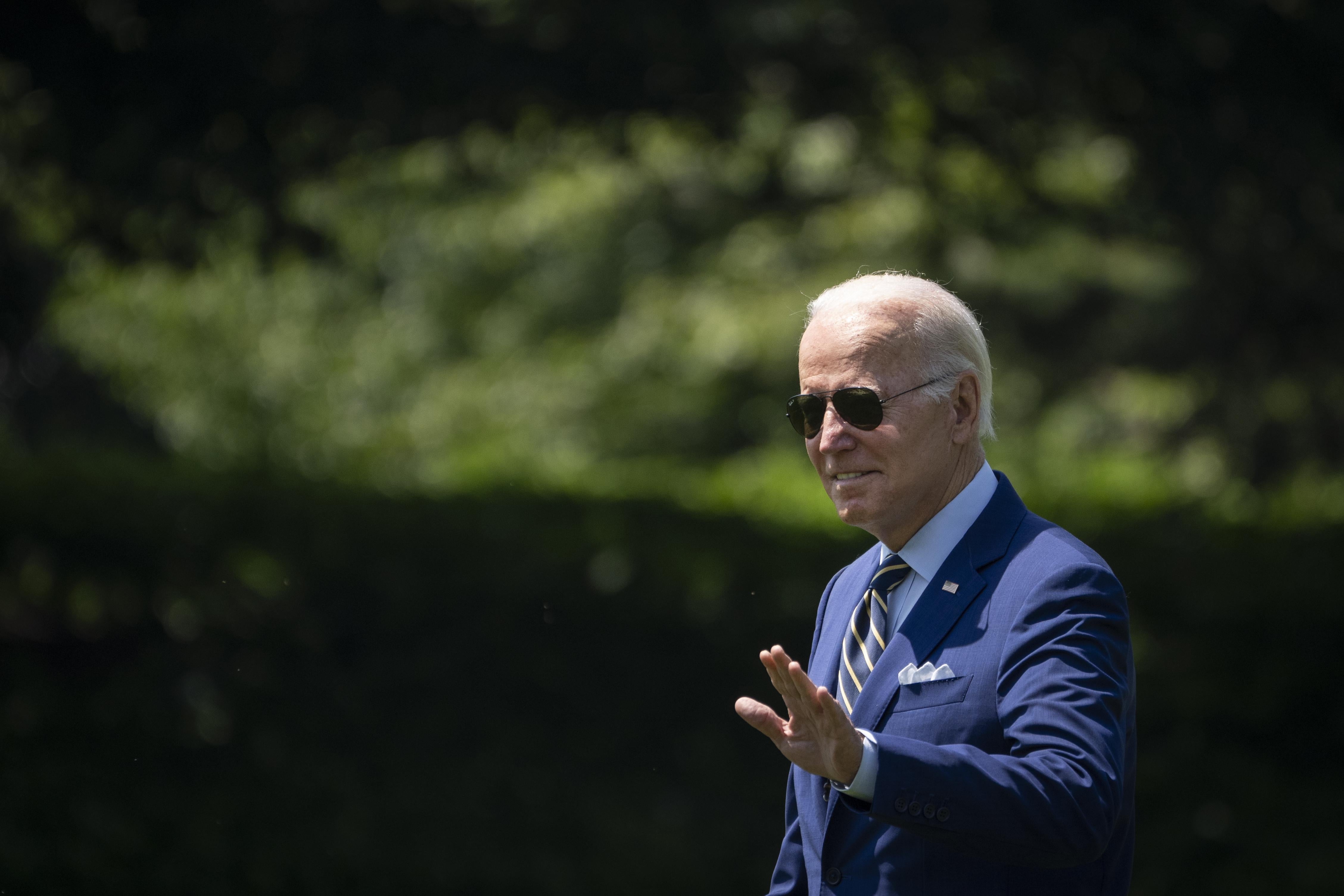 President Joe Biden walks while wearing aviator sunglasses.