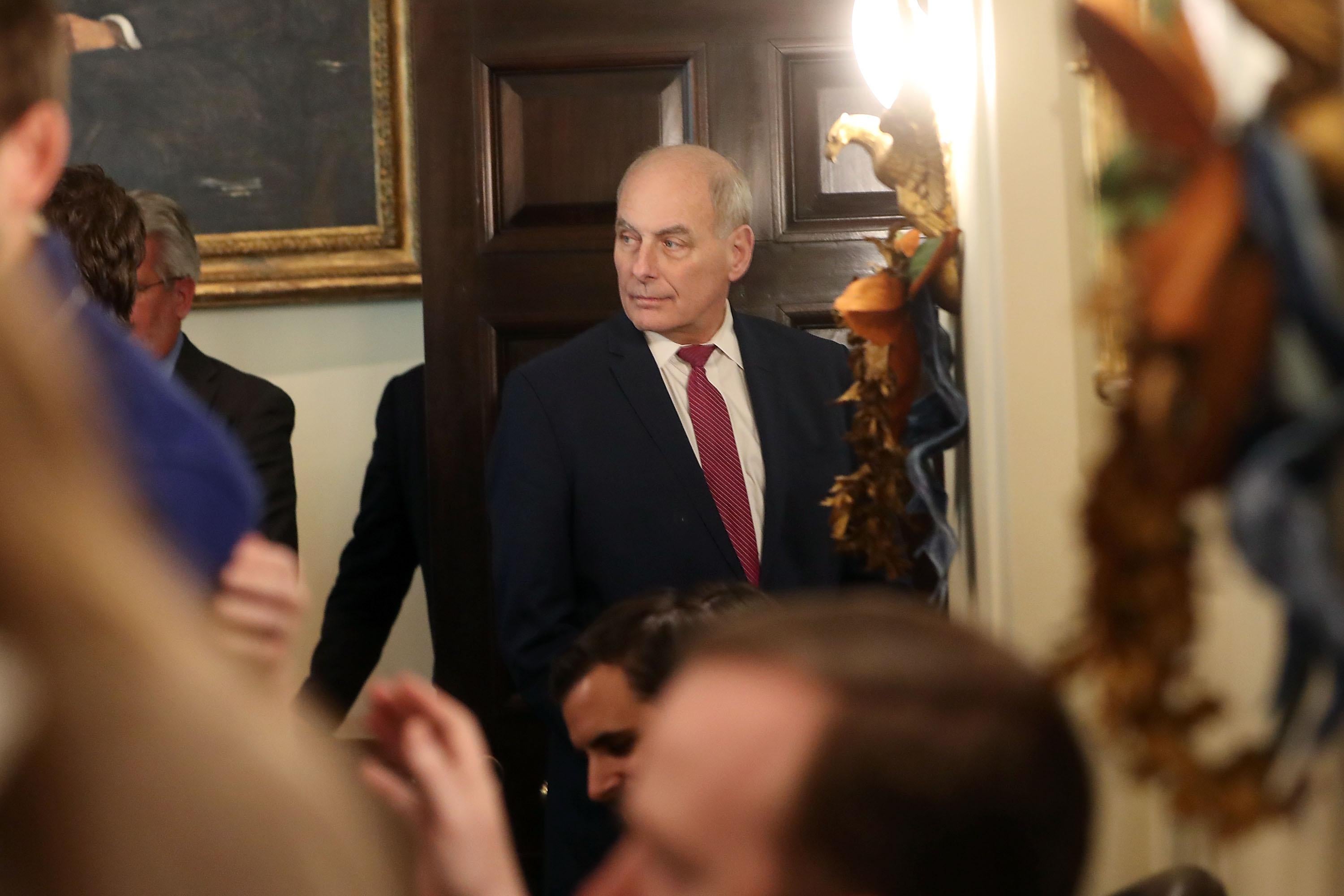 John Kelly looks to the side in a crowded room in the White House.