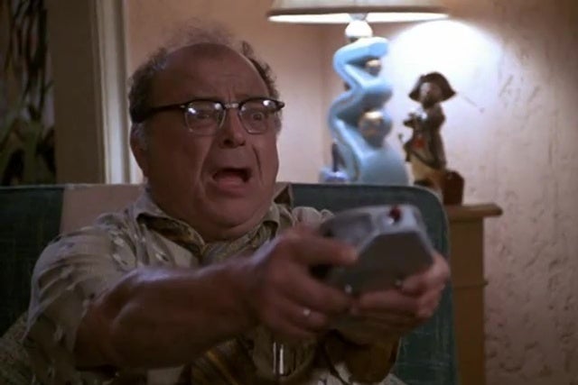 Sydney Lassick holds a remote in front of him in disbelief, in a still from Remote Control Man.