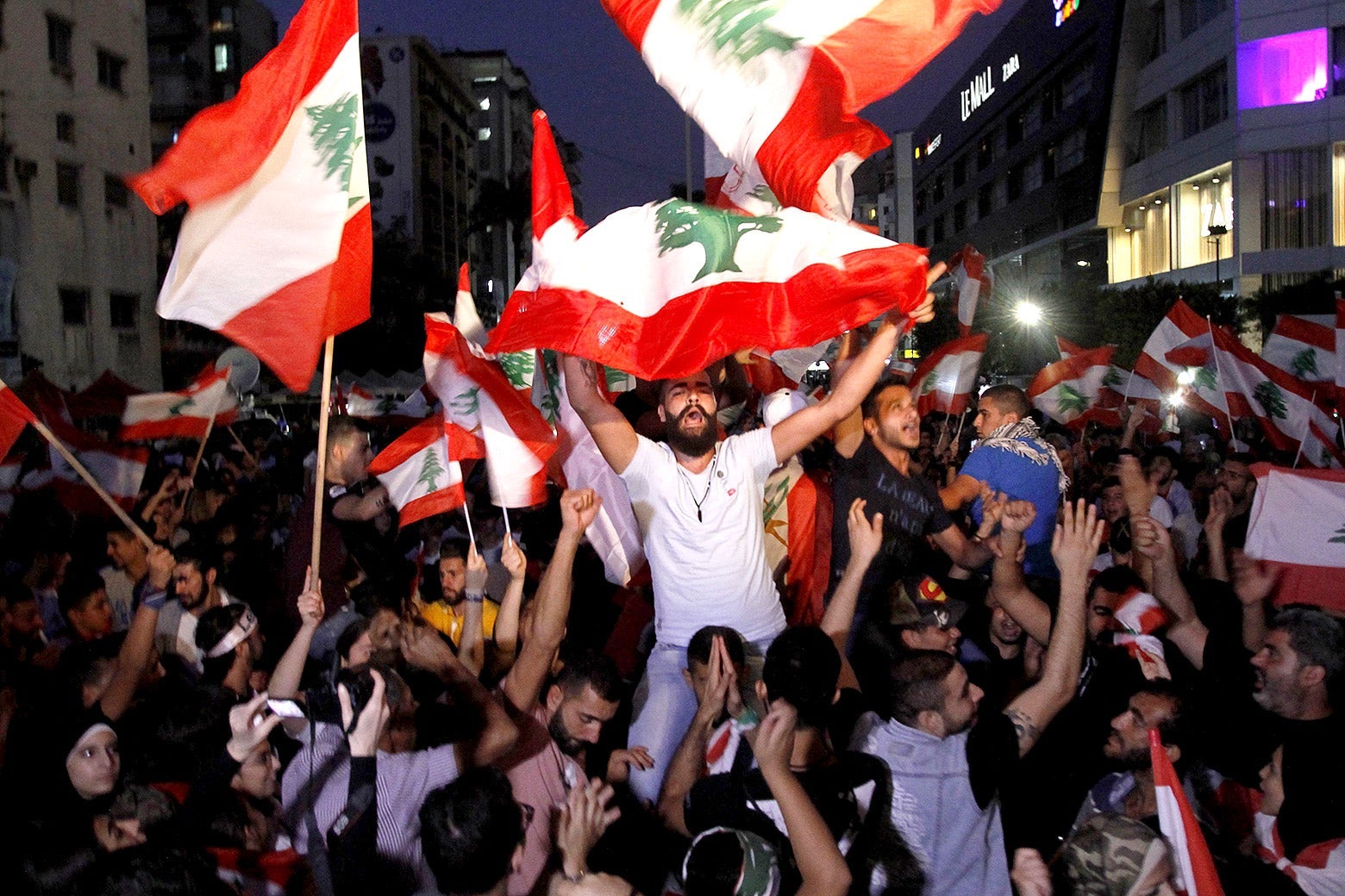 Lebanese protesters gather in Sidon on Monday. They are holding flags and chanting.