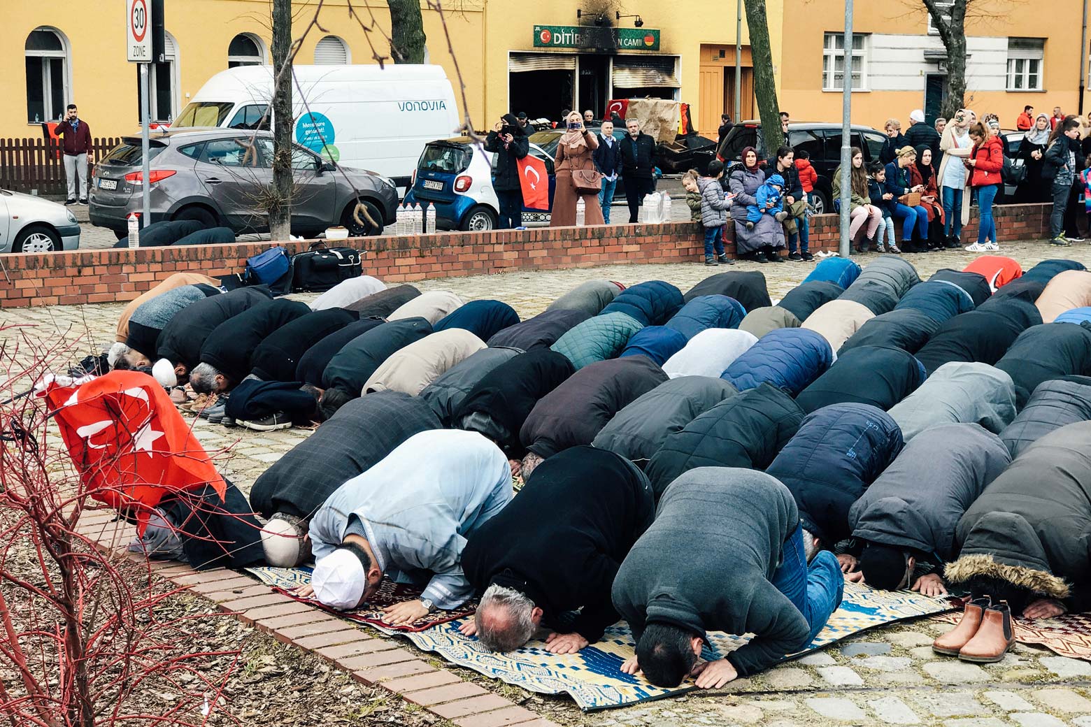 People pray near a mosque after it was destroyed by a fire in Berlin on March 11.
