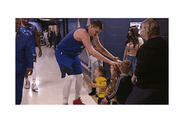 Jokić, wearing a blue jersey, playfully picks up kids.