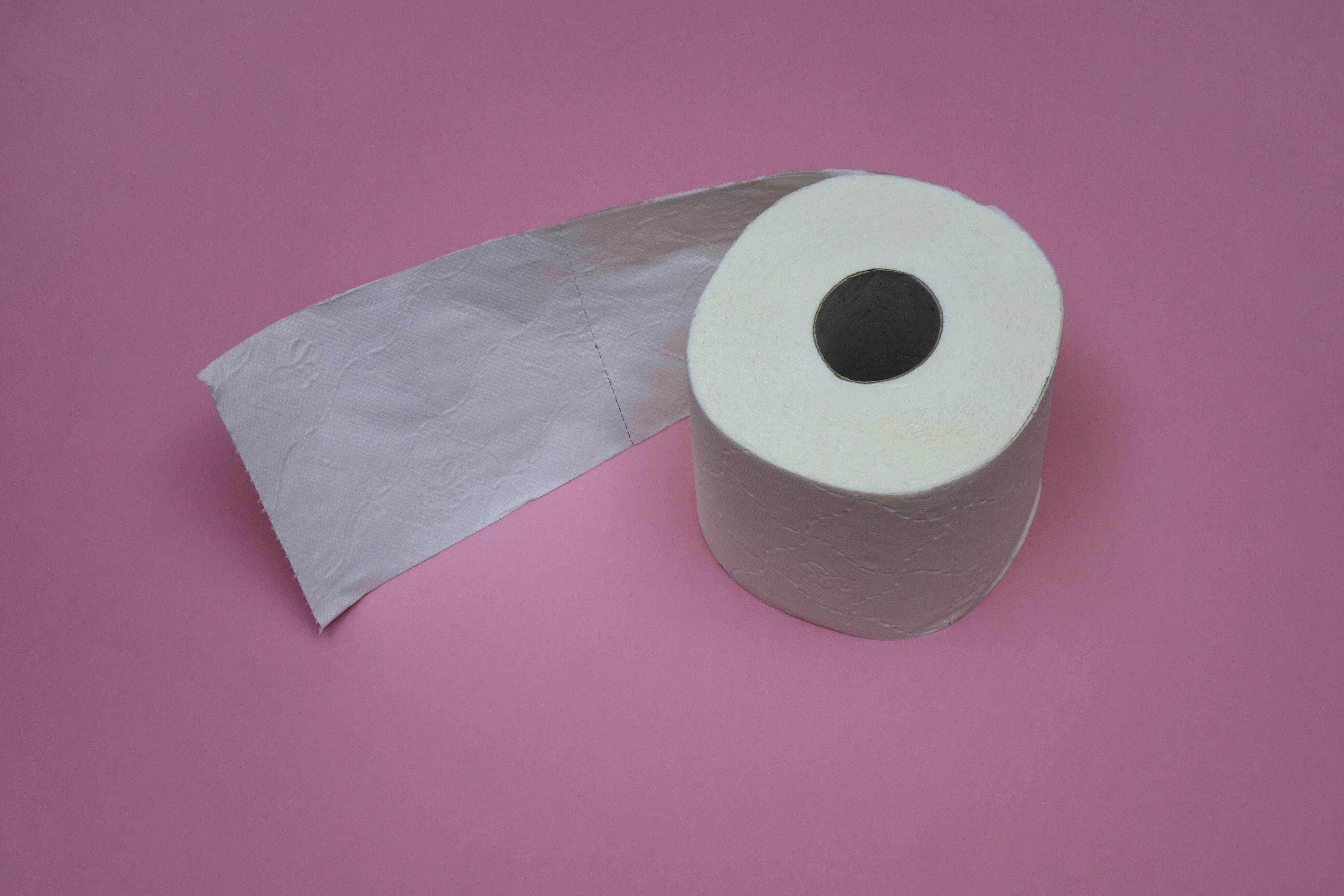 A toilet paper roll on a pink surface