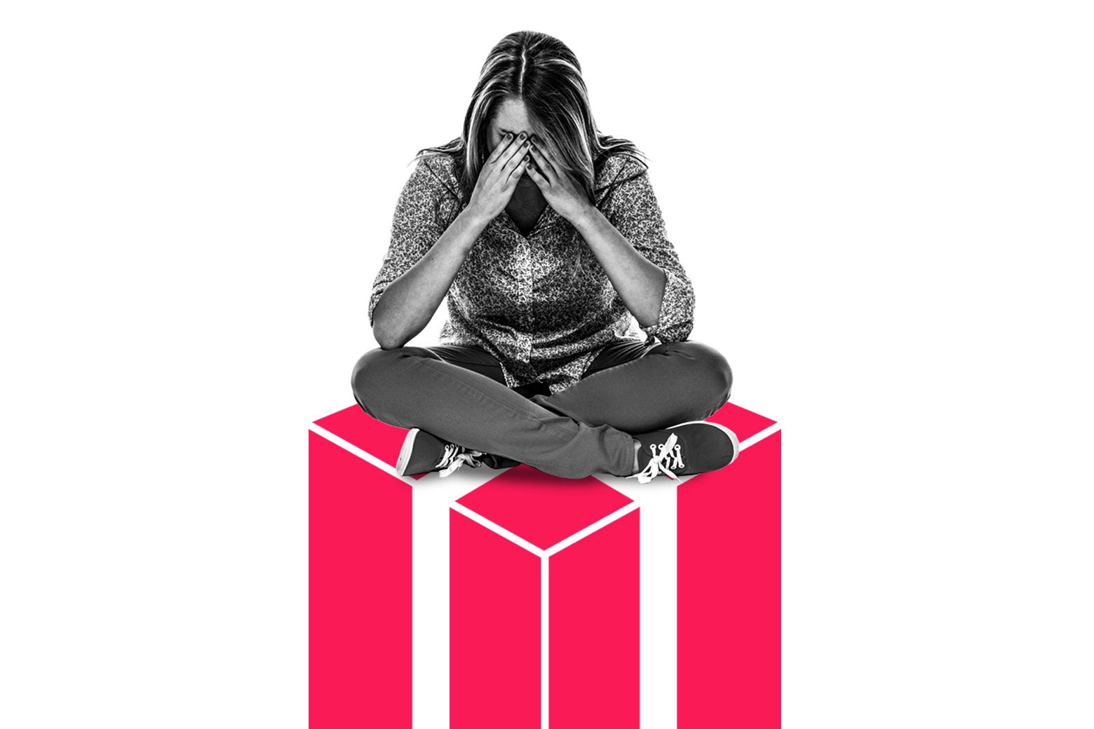 A woman sits with her hands over her face on top of an illustrated present.